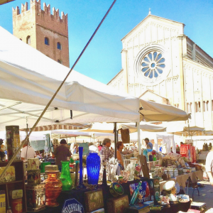 Mercato dell'antiquariato a San Zeno, foto di una bancarella con la chiesa di San Zeno sullo sfondo